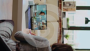 Vertical video Teleworking team leader in cozy apartment discussing with coworkers in videocall