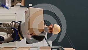 Vertical video Warehouse intern seals cardboard boxes