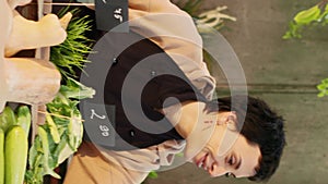 Vertical video: Woman stand holder wearing apron running farmers market counter