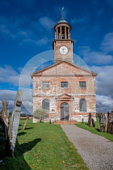 Vertical view of the building and cemetery stones of Kirkandrews under the blue sky in Carlisle