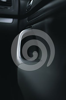 Vertical view of car door silver handle with black textured fabric