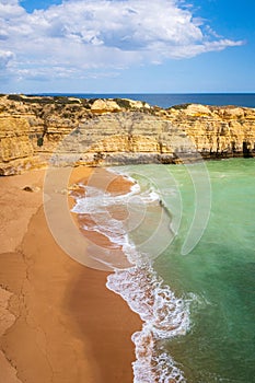 Vertical view of cliffs and ocean waves crashing onto beach near Albufeira, Portugal photo