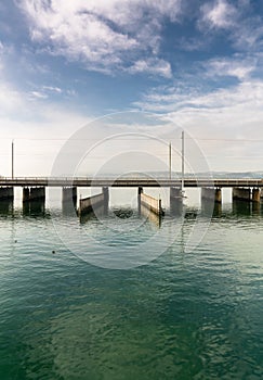 Vertical view of a concrete bridge over water with a train line and road running parallel and a boat and ship passageway below