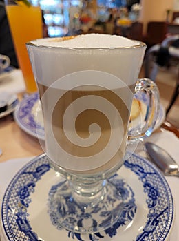 Vertical view of a cup of cappuccino coffee on a saucer and a wooden table