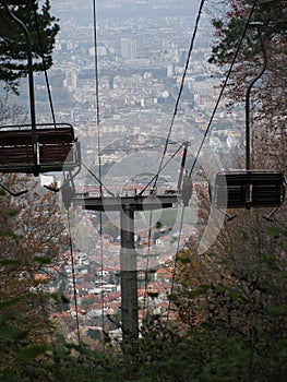 Vertical view of the empty cabins and wires of telecabin before the cityscape