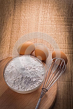 Vertical view flour in bowl corolla eggs on wooden