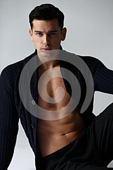 Vertical view. Handsome man with naked torso in black clothes, looking at camera,  on white background.