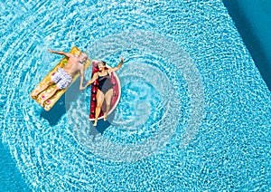 Vertical view of happy couple of old senior people enjoying the summer holiday vacation at the blue water pool with coloured treny