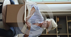 Vertical view happy older woman unpack received parcel box