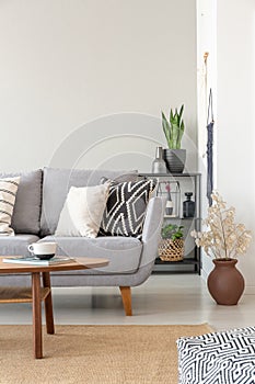 Industrial living room with grey couch with patterned pillows, real photo with copy space on the wall