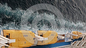 Vertical view of Lifeboat on giant cruise ship view down to ocean surface with waves below while ship cruising saling in the sea.