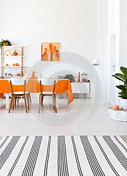 Living room with long table, chairs and orange details. Real photo concept