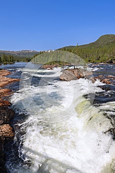 Vertical view of the Namsen River in Namsskogan, Trondelag, Norway, featuring cascades over large stones