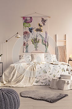 Vertical view of a pastel bedroom interior with a big bed in the middle and a painted fabric art on the wall