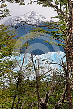 Vertical view of Perito Moreno Glacier and snowy mountains, in El Calafate, Argentina, against a grey and cloudy sky.