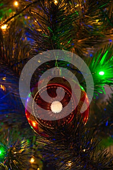 Vertical view of red christmas ball and garland lights on Christmas tree. New year card, selective focus