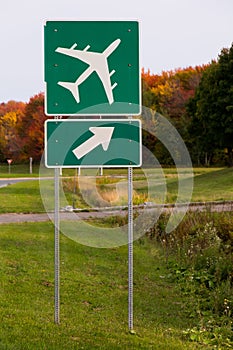 Vertical view of roadside airport sign with fall foliage in the background