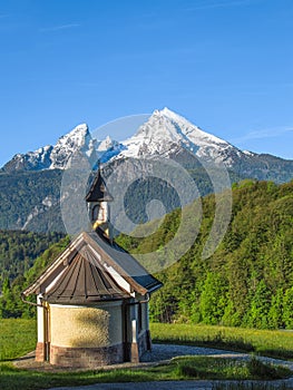 Vertical view of small chapel and snowy summit of Watzmann mount
