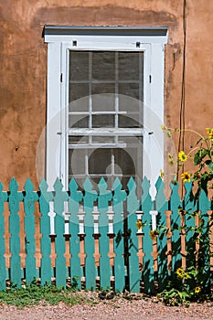 Vertical view of sunflowers, fence, window, adobe wall in Santa Fe, NM