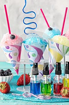 A vertical view of various snow cones with flavoured syrups in front. photo