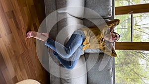 Vertical view woman relaxing on sofa at modern home