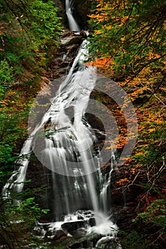 Vertical of waterfall flowing down the rocks in a forest in autumn shot in long exposure