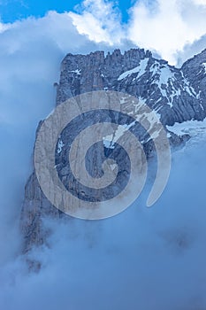 Vertical of the Wetterhorn peak of the Swiss Alps captured surrounded by smoky clouds