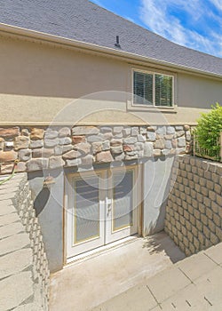 Vertical Whispy white clouds Basement entrance with glass panels on the double doors