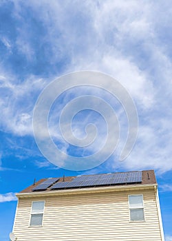 Vertical Whispy white clouds Low angle view of two houses with wood vinyl sidings and solar panels on roof at Utah