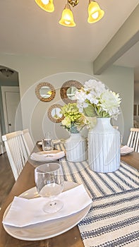 Vertical White dinnerware and table runners at the dining room of a family home
