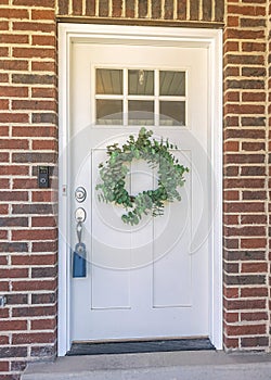 Vertical White door exterior with glass panel above the wreath and lockbox