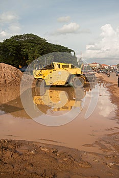 Vertical wide view of muddy roadside construction vehicles with sunny skies