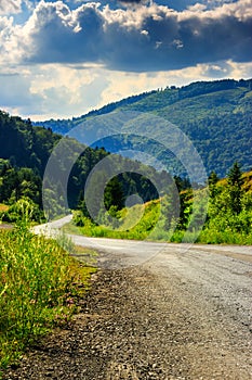 Vertical winding road goes to mountains under a cloudy sky