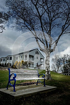 Vertical of a wooden bench against a house in New England, Maine on a cloudy day