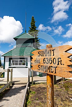 Vertical of a wooden tablet "summit 6360ft" building with green trees on a sunny day in Canada