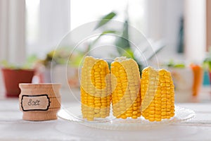 vertically built boiled corn next to a jar of salt on the background of the window