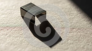 Vertically, casting a long shadow on a textured, light-colored