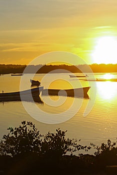 Vertically exposed golden silhouette of two fishing boats at dawn.