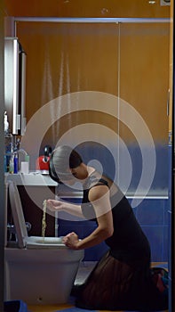 vertically. a man disguised as a woman eating noodles from the toilet