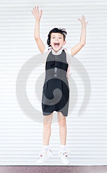 Verticsl portrait of 9 years old happy caucasian jumping school girl on white background with hands up. Happy girl wants to learn.