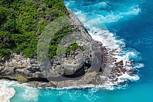 Vertiginous, swirling foamy water waves at the ocean photographed from above cliff.