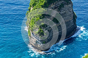 Vertiginous, swirling foamy water waves at the ocean photographed from above cliff.