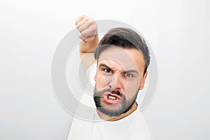 Very angry man looks on camera. He is ready to fight with fist. He poses. Isolated on white background.