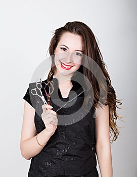 Very attractive and stylish professional hairdresser woman with scissors in right hand and comb in left. hairdresser