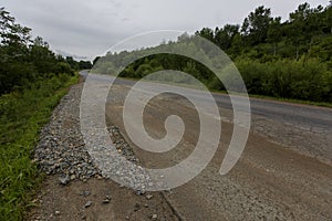 Very bad road in Russia. The asphalt road is all in holes in the middle of the forest.