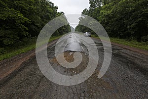 Very bad road in Russia. The asphalt road is all in holes in the middle of the forest.