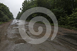 Very bad road in Russia. The asphalt road is all in holes in the middle of the forest.