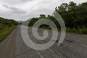 Very bad road in Russia. The asphalt road is all in holes in the middle of the forest.