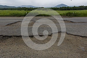 Very bad road in Russia. The asphalt road is all in holes in the middle of the forest.