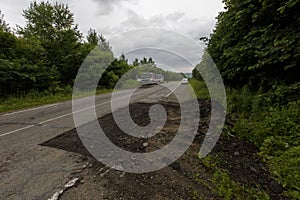 Very bad road in Russia. The asphalt road is all in holes in the middle of the forest.